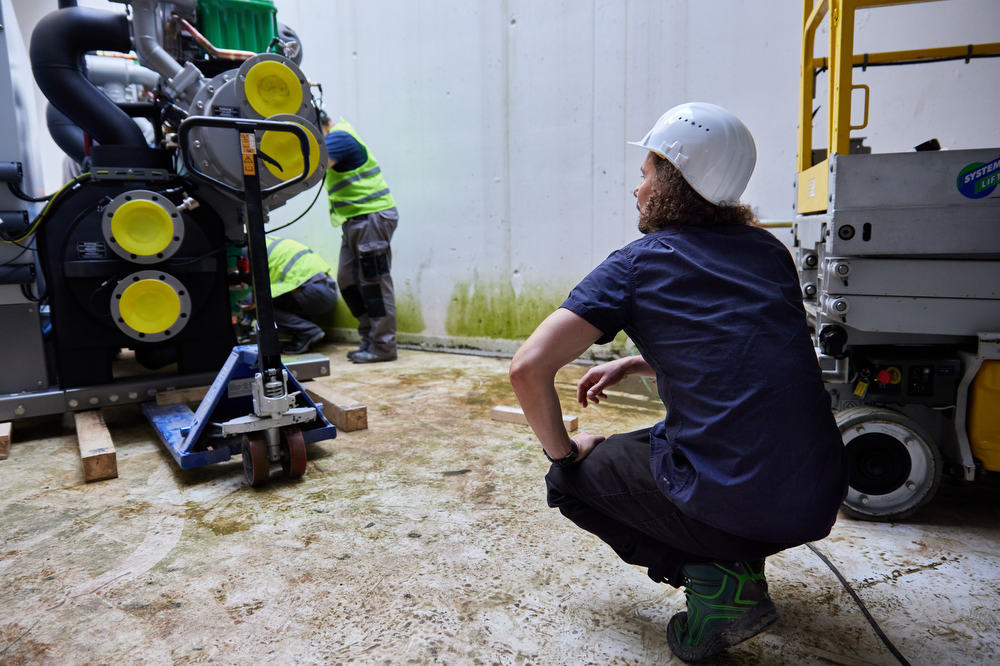 Großanlieferung per Kran in den Technikkeller. Ein Ingenieur kontrolliert die Arbeit.