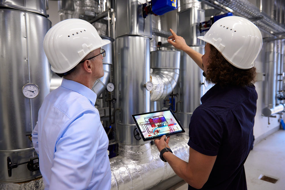 Energietechnik Ingenieure sprechen vor einer Anlage mit Tabel im Hand